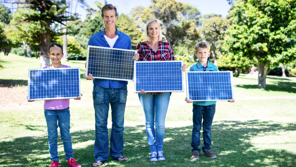 család kézben tartja a napelem paneleket, boldog mosollyal az arcukon